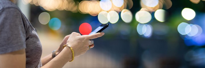 Woman looking at mobile phone with lights in the background