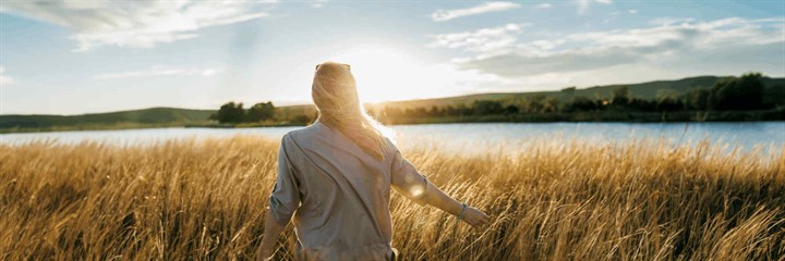 Woman walking in cornfield in the sunshine