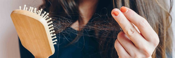 Close up of woman pulling hair out of a brush