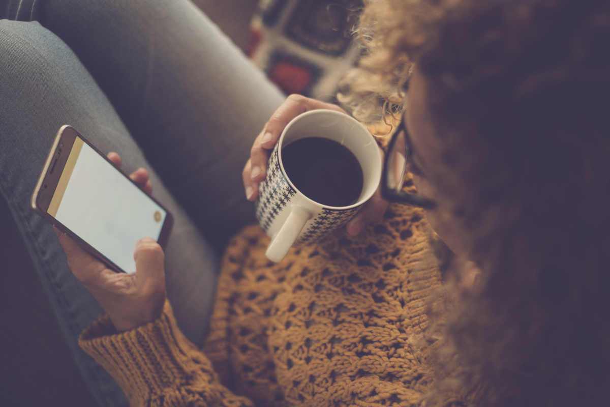 Overhead view of a woman drinking coffee looking at phone