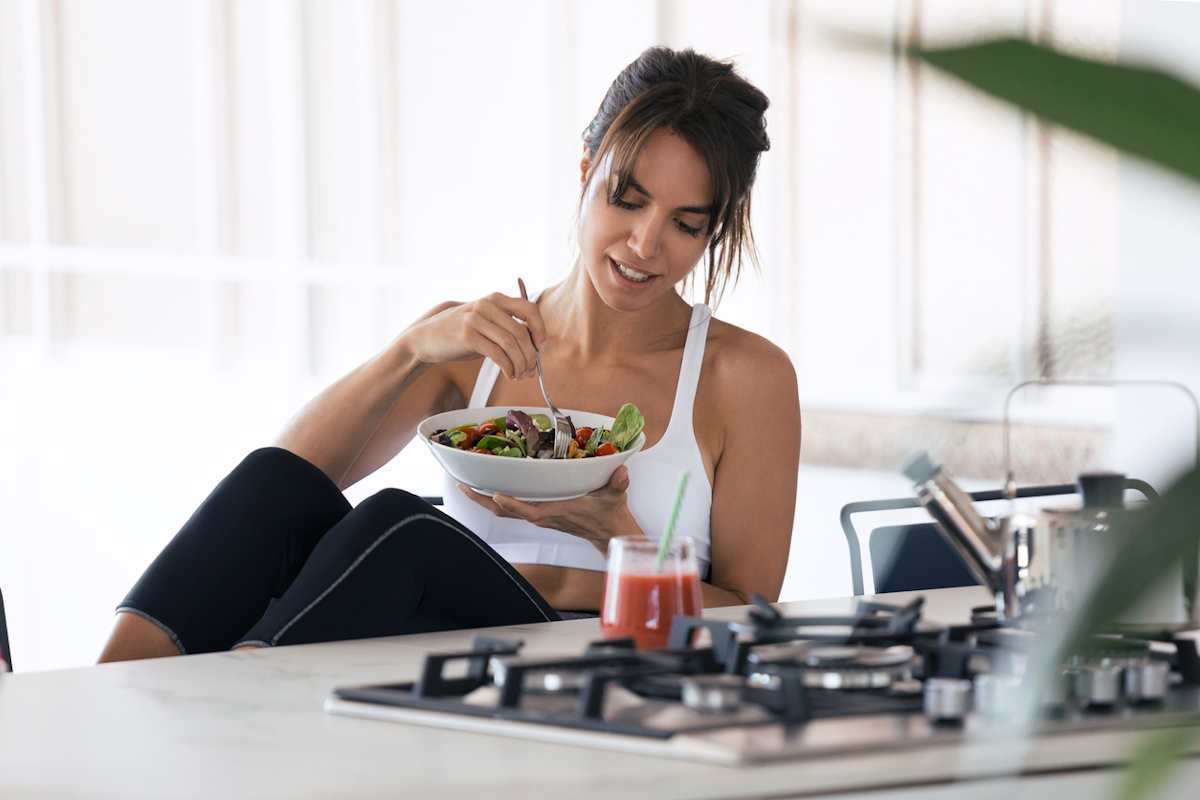 Young woman in sports gear eating breakfast
