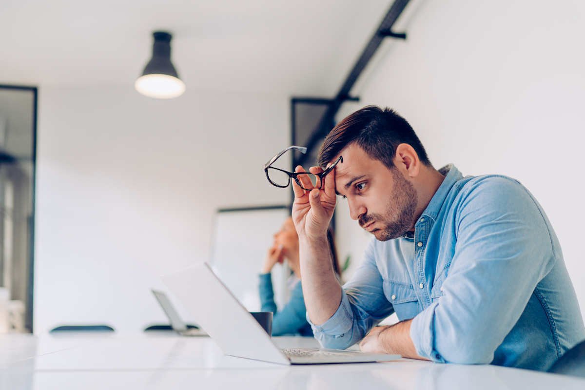 Man holding glasses staring at laptop