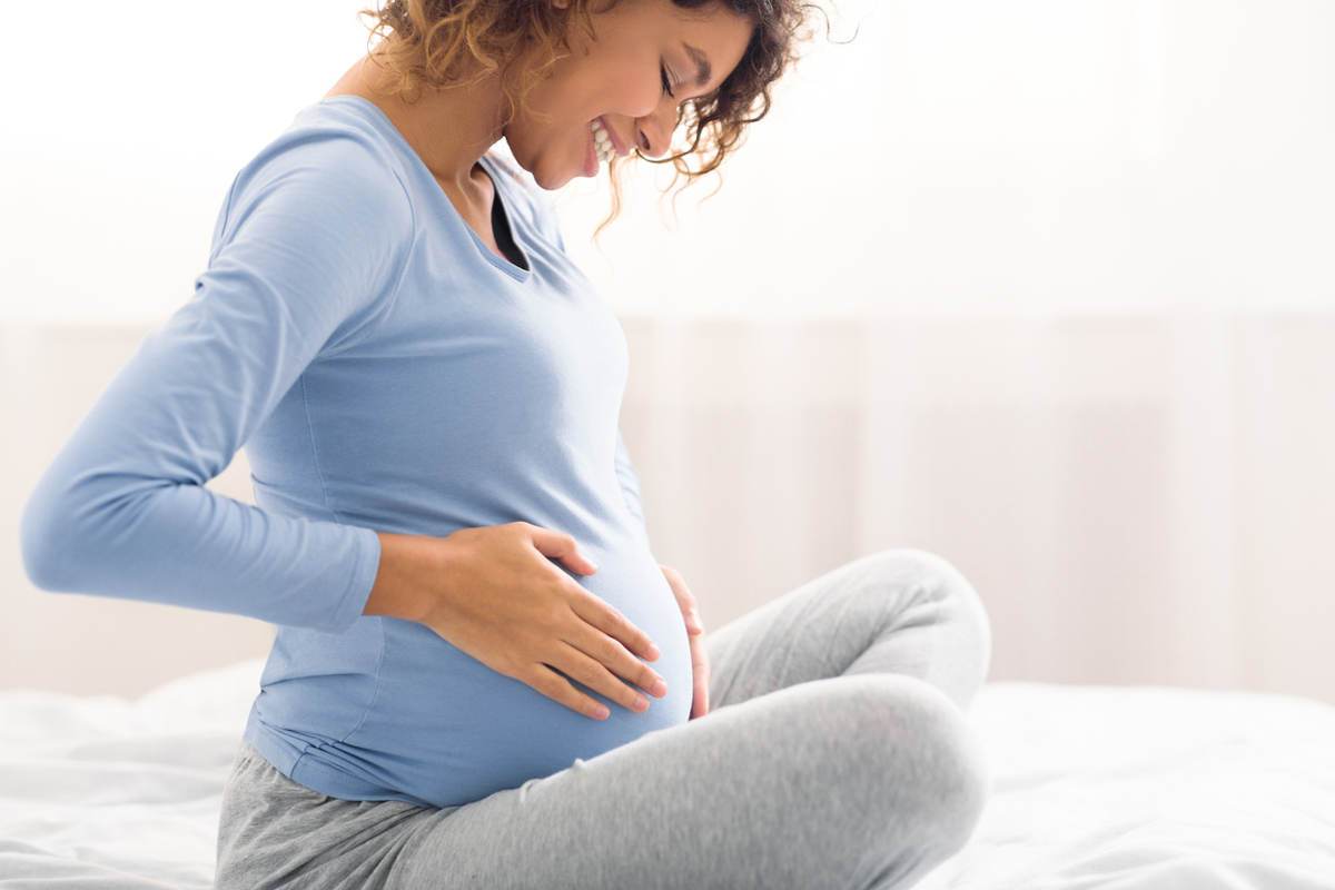 Smiling pregnant woman holding her stomach