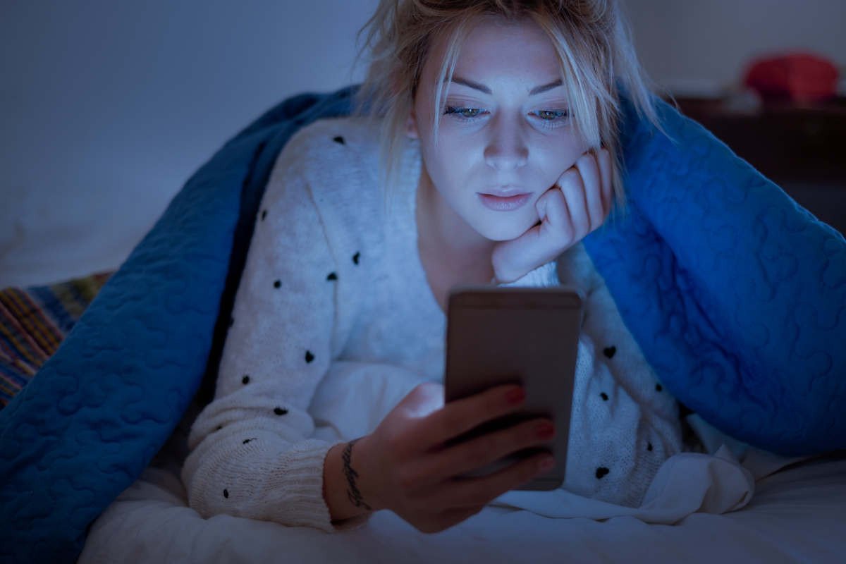 Woman in bed staring at her phone